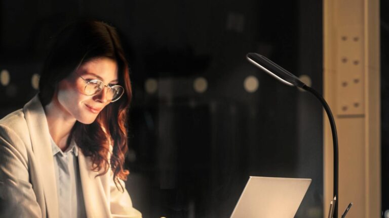 A lady wearing glasses whuile looking at her computer